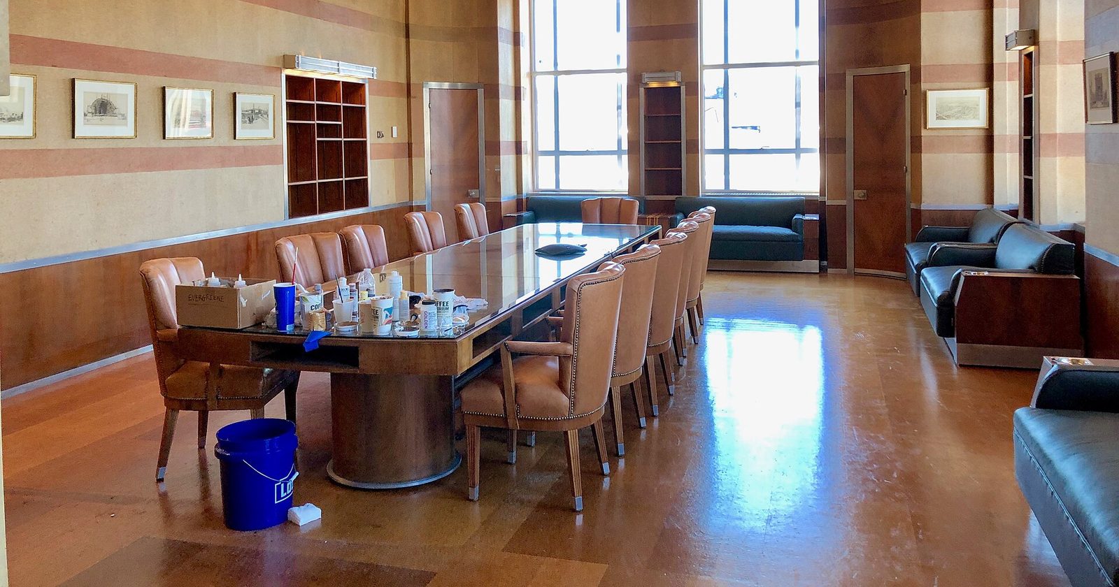 Reprezentacyjna sala posiedzeń z długim stołem i rzędem skórzanych foteli przy wysokich oknach